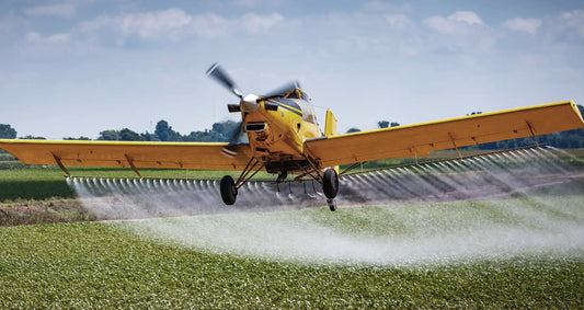 Small plane spraying glyphosate over green landscape